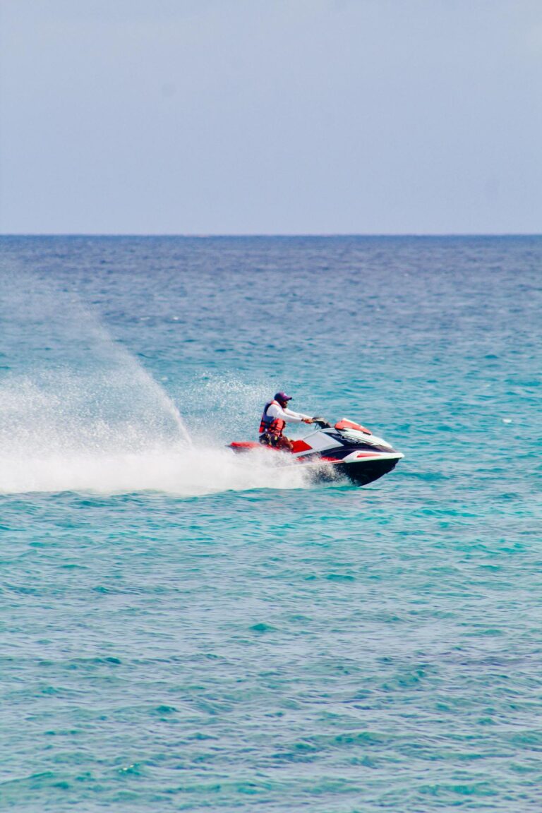 Action shot of a man enjoying jet skiing on clear, blue ocean waters under a sunny sky.