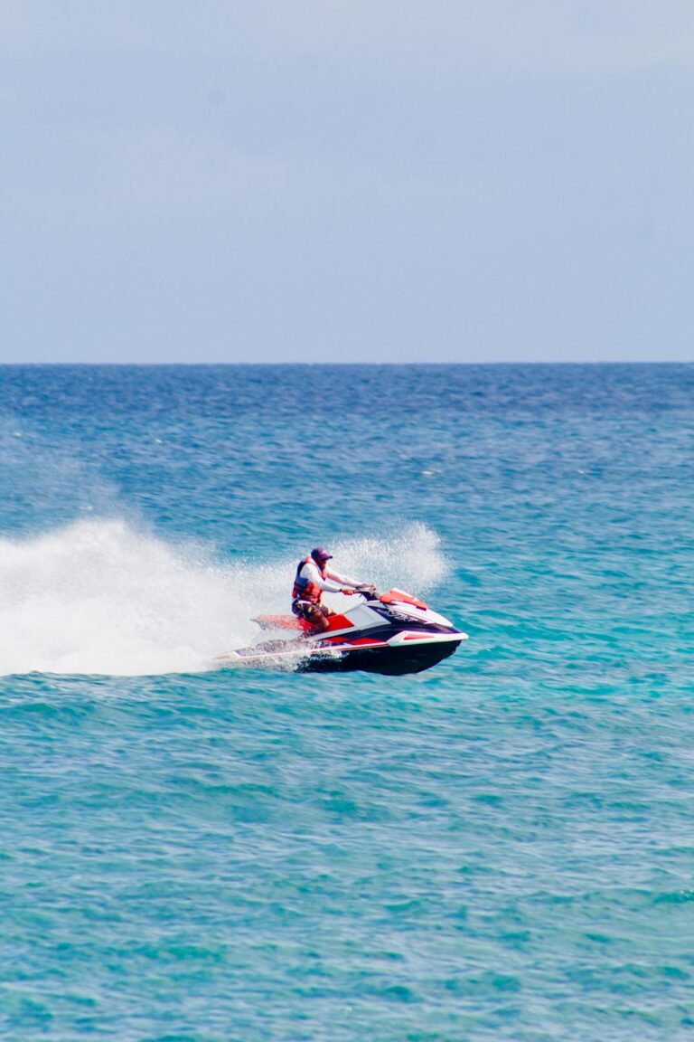 Exciting image of a man on a jet ski speeding across the vibrant blue ocean.