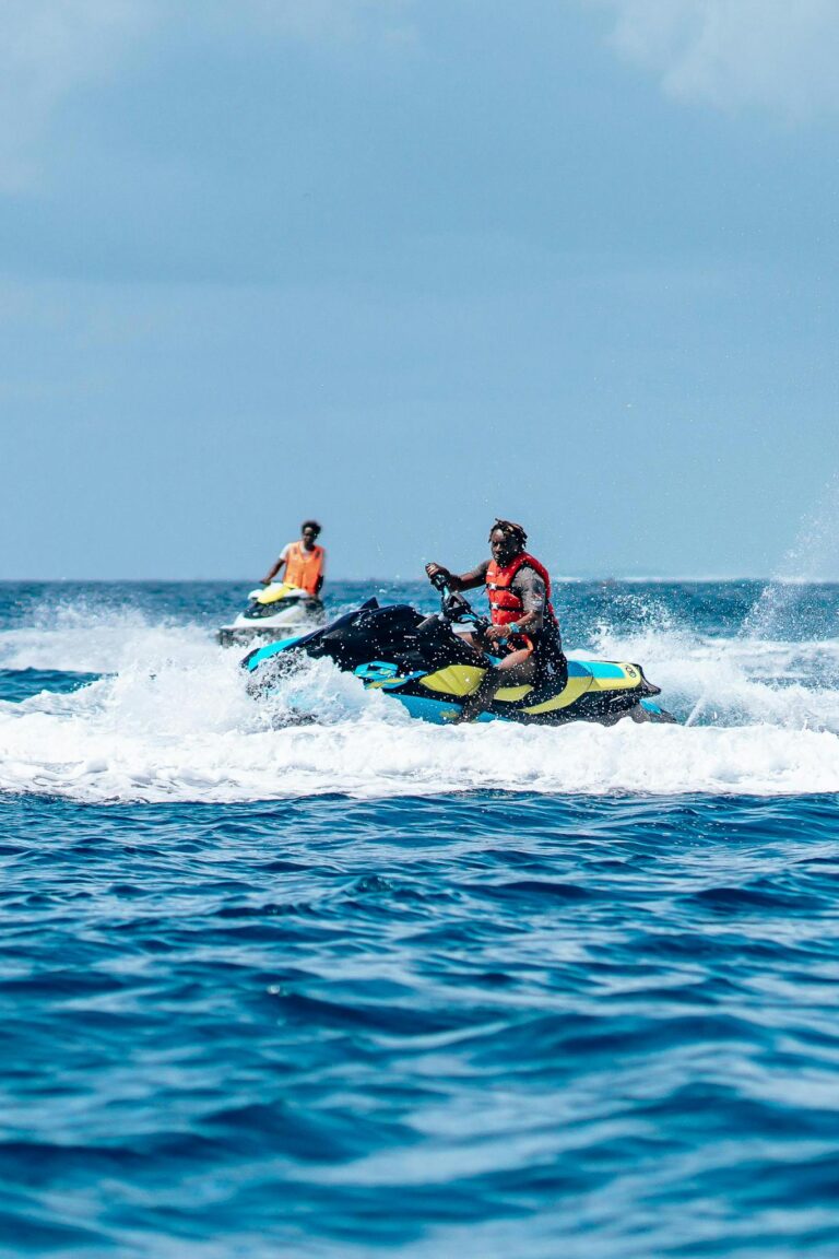Two adults enjoying a thrilling jet ski ride on a vibrant blue ocean.
