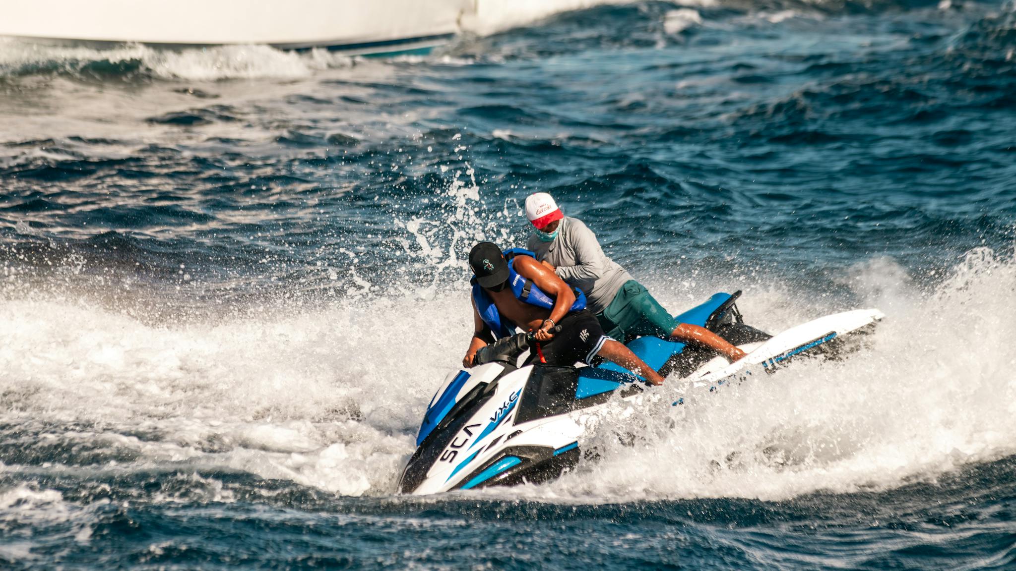 Two people enjoy a thrilling jet ski ride amidst ocean waves in Cabo San Lucas, Mexico.
